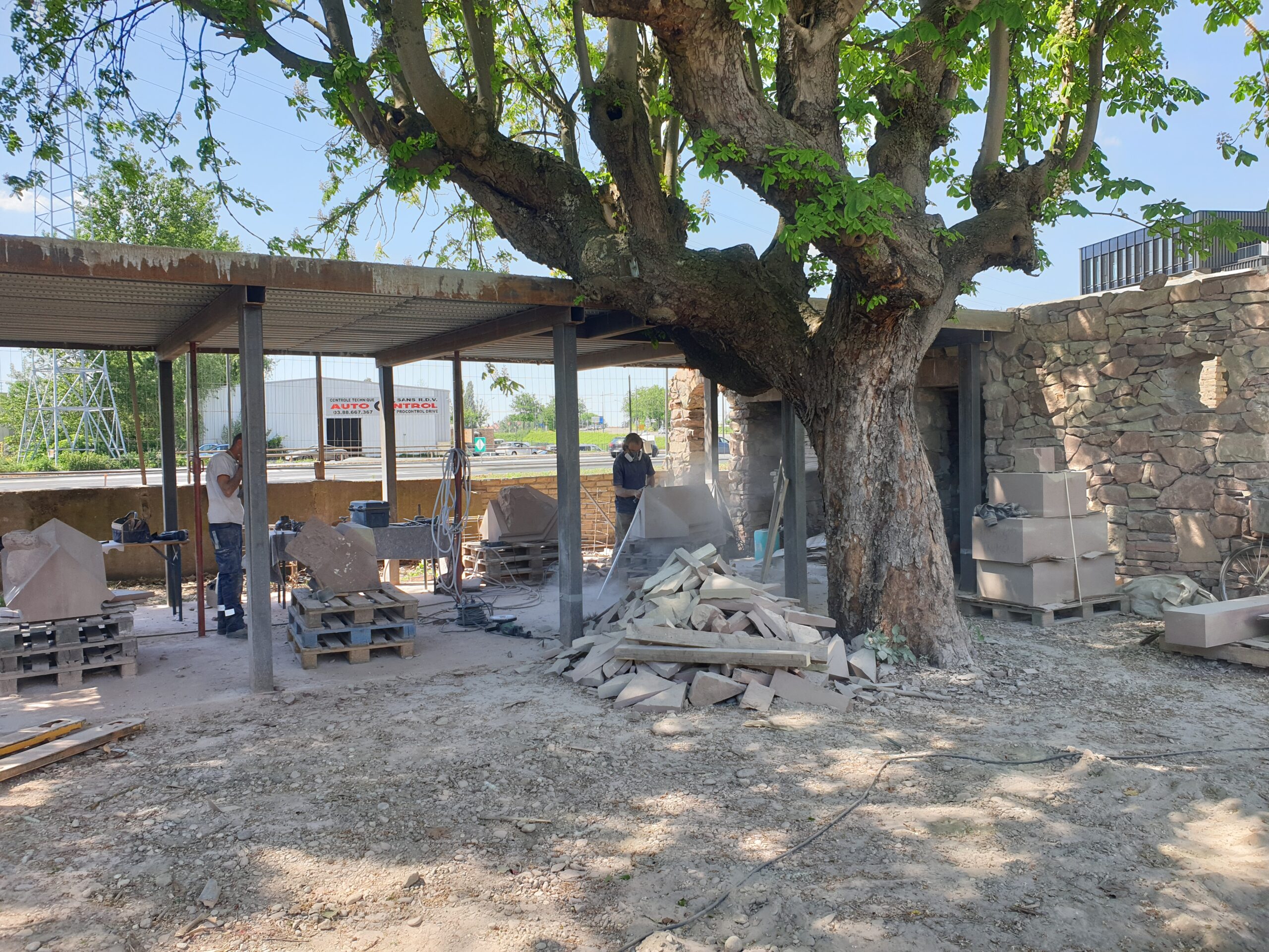 Die Steinmetze arbeiten im Hinterhof des Schutzenberger-Hauses unter einem Baum