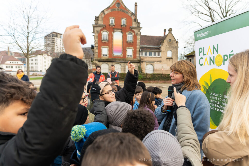 Les enfants de l'école du Rhin posent des questions sur le parc du Petit Rhin à Suzanne Brolly, on distingue la maison Rhein Fischer en fond