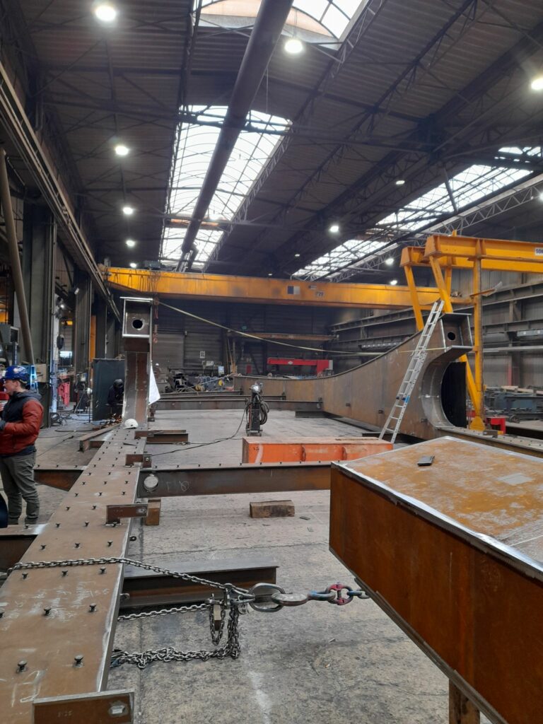 Vue d'ensemble de l'entrepôt. Prêt de 20m de haut à son faite, des grues jaunes le traverse de part en part pour permettre le treuillage des pièces.