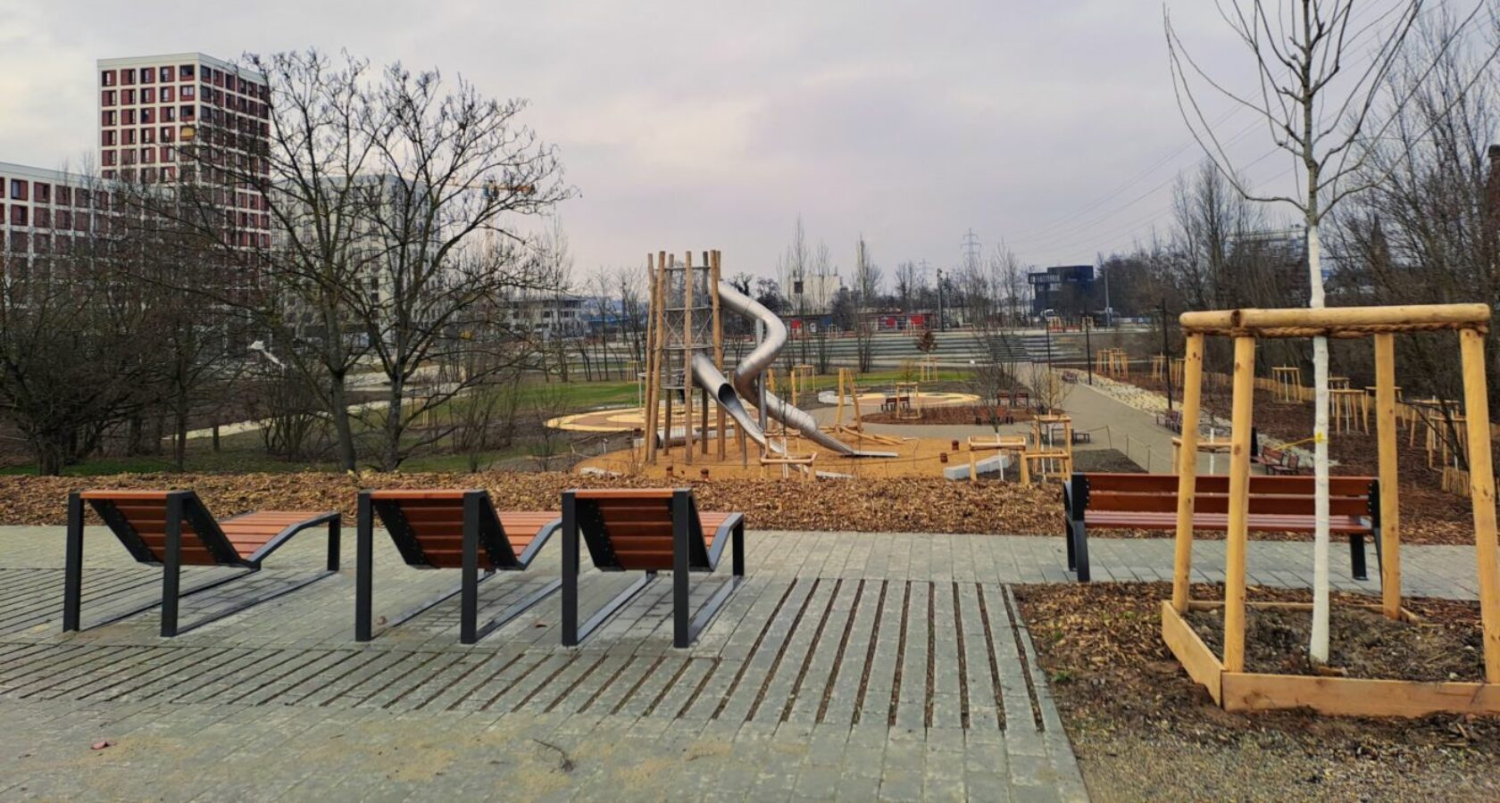 Trois chaises longues et un arbre en premier plan, en surplomb du parc et des toboggans