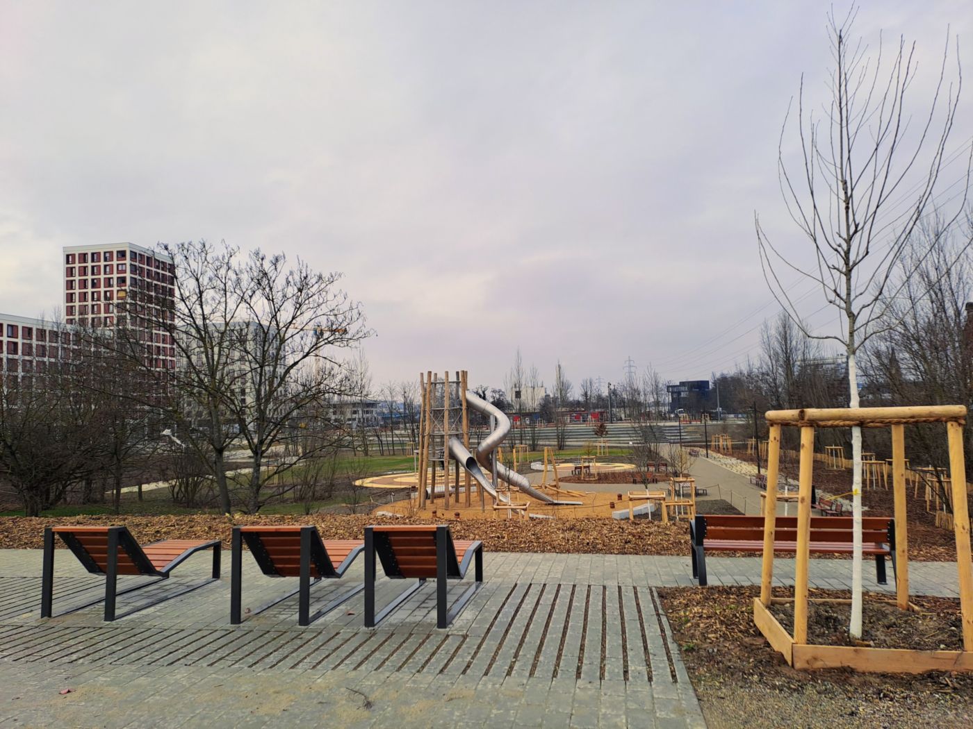 Trois chaises longues et un arbre en premier plan, en surplomb du parc et des toboggans