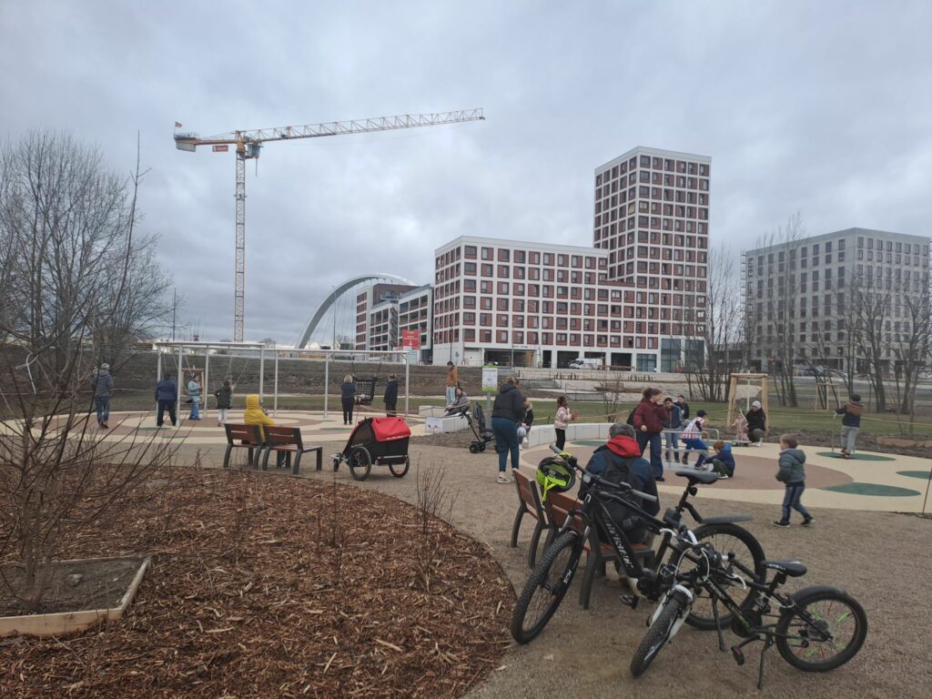 Des vélos et des enfants à côté du tourniquet et des balançoires du Parc du Petit Rhin