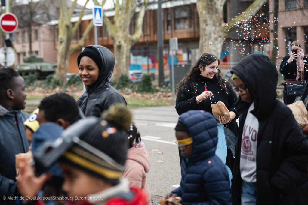 On voit des enfants en premier plan et une animatrice sous un jet de confettis