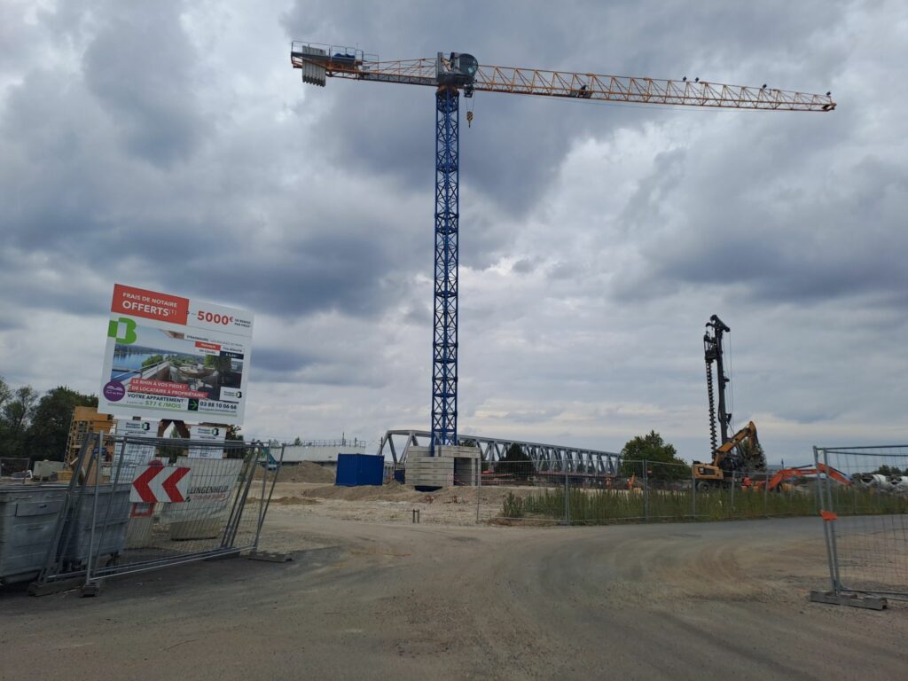 Une grue et un panneau de chantier proposant à la vente les appartements de l'opération Les escales du rhin